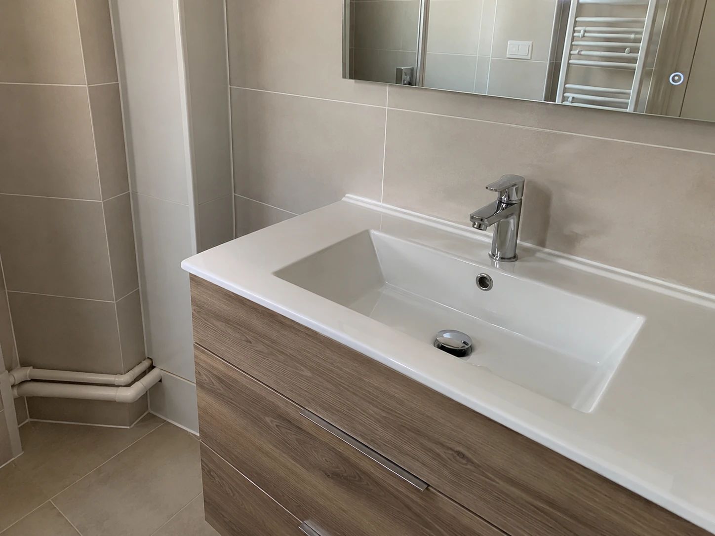 Meuble vasque en bois avec plan céramique, mitigeur chromé, faïence beige grand format et miroir