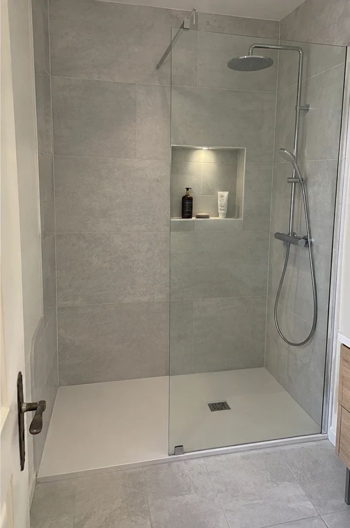 Après : douche avec receveur extra-plat, carrelage gris grand format, niche éclairée et paroi vitrée